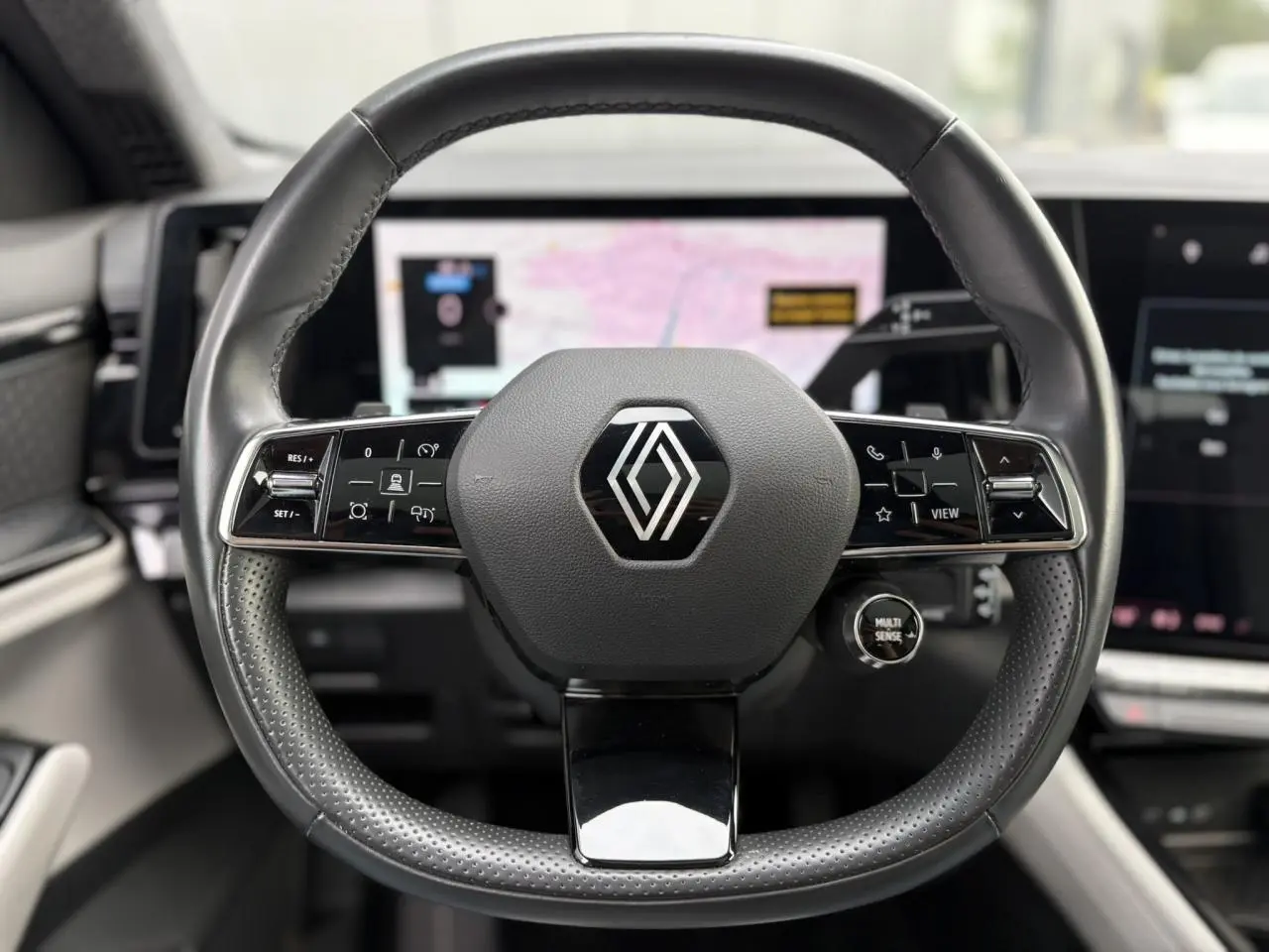 Volant cuir noir perforé avec commandes intégrées et logo Renault, intérieur moderne du Renault Espace 2023.