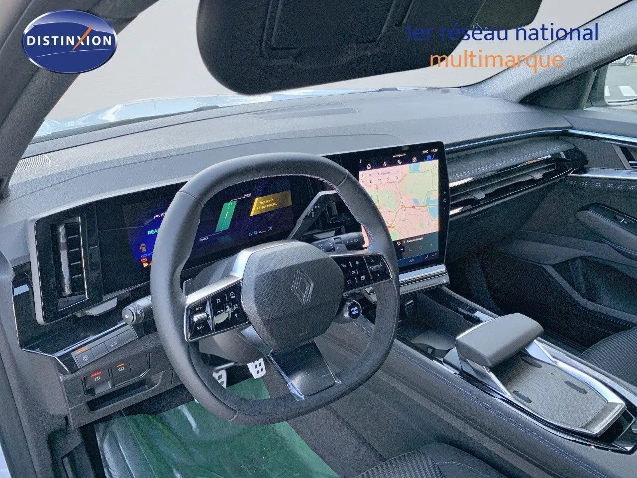 Vue intérieure du tableau de bord et volant du Renault Austral 2024 hybride, finition Iconic Esprit, avec écran tactile et cuir noir.