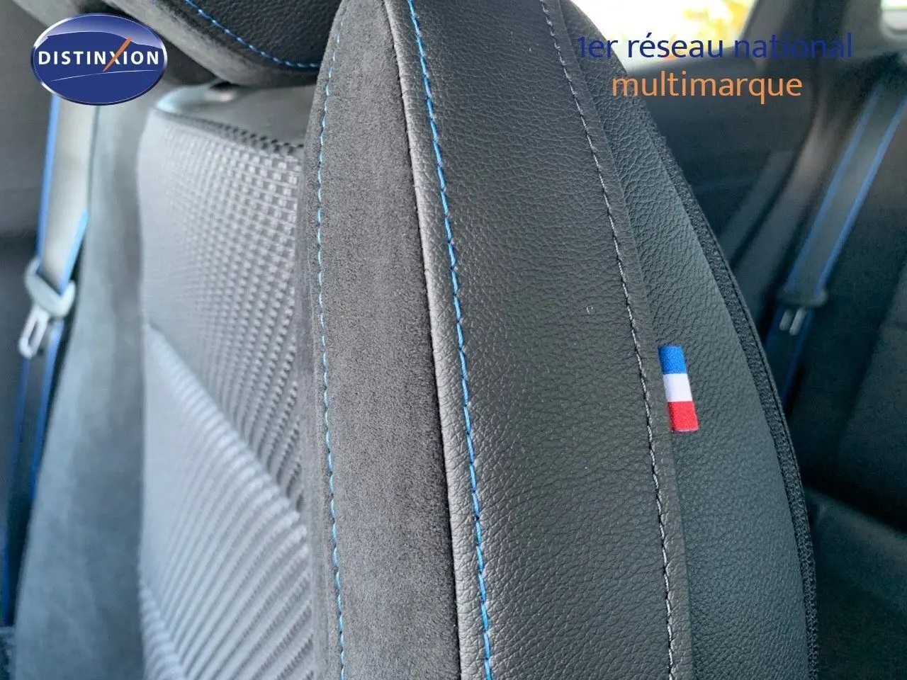 Gros plan sur la sellerie noire avec surpiqûres bleues et drapeau tricolore français sur le siège avant d'un Renault Austral 2024.