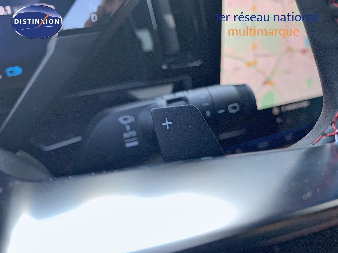 Gros plan sur la palette de changement de vitesse "+" du volant d'un Renault Austral 2024 hybride essence blanc métal avec toit noir.