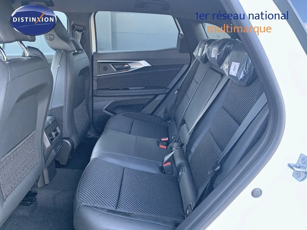 Vue intérieure côté droit des sièges arrière noirs en tissu et cuir du Renault Austral blanc métal 2024 avec toit noir.