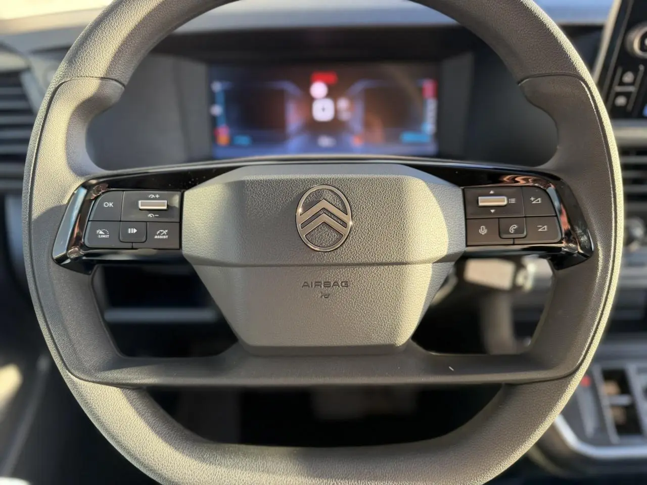 Gros plan sur le volant multifonction noir du Citroën Jumpy XL 2025 avec tableau de bord numérique en arrière-plan flou.