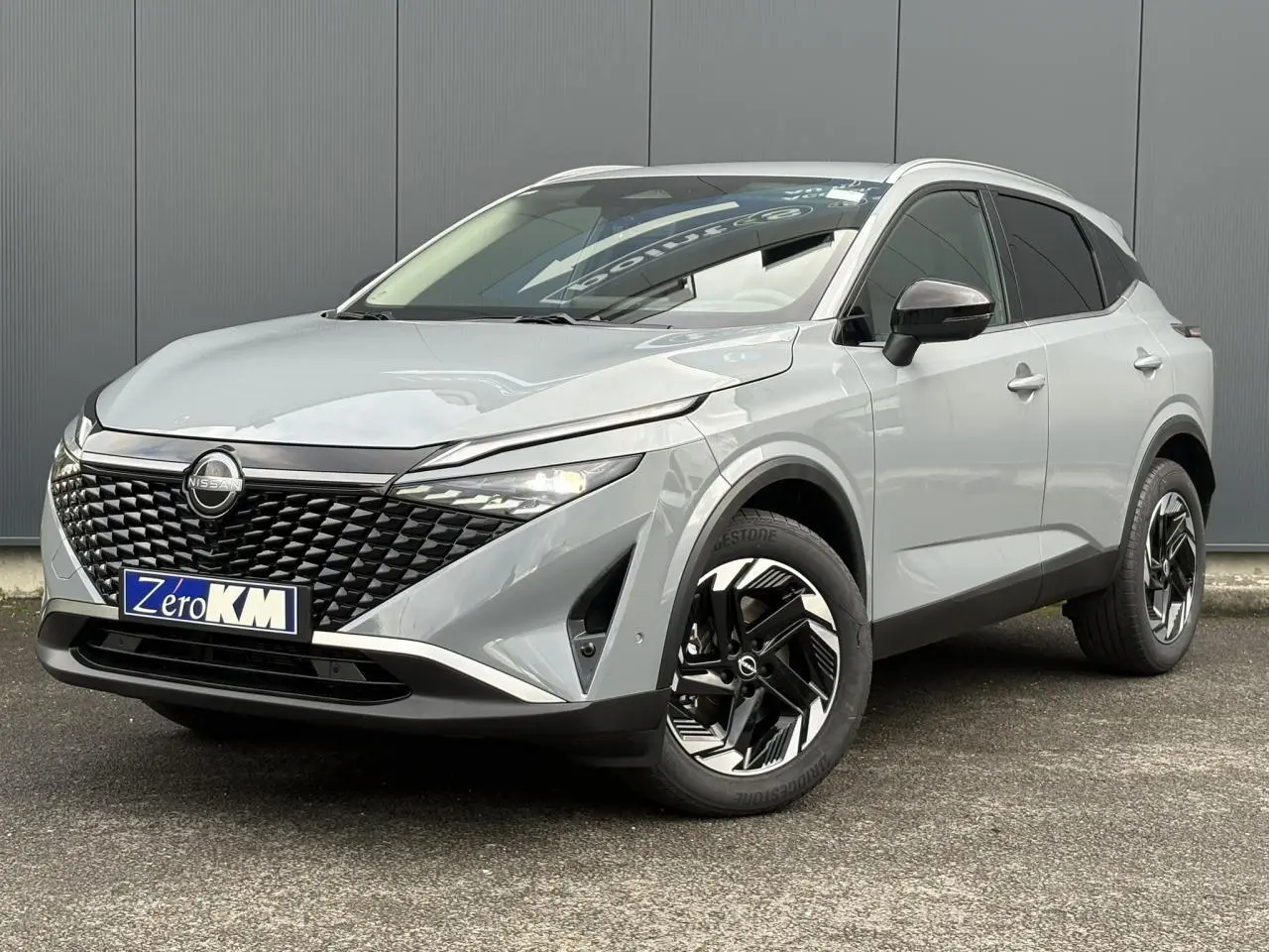 Nissan Qashqai III e-Power gris Ceramic en 3/4 avant droit, avec calandre noire et jantes alliage bicolores.