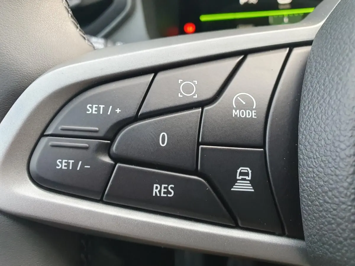 Gros plan sur les commandes du régulateur de vitesse au volant du Dacia Bigster, finition noire et gris argenté.