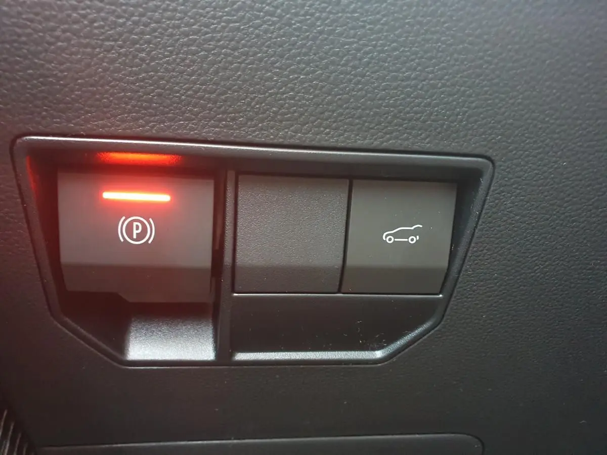 Boutons de commande du frein de parking électrique et ouverture du coffre sur tableau de bord noir d'une Dacia Bigster.