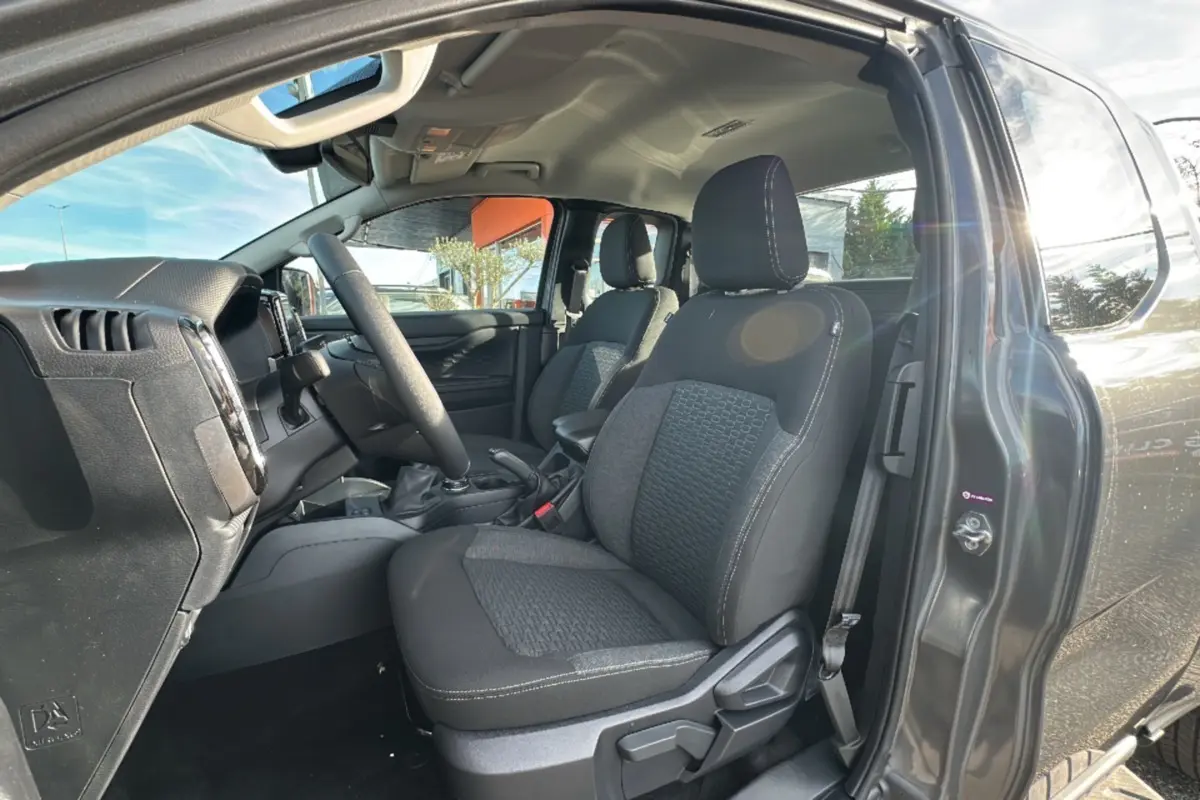 Vue intérieure côté conducteur du Ford Ranger gris carbone 2025, mettant en valeur les sièges avant et le volant multifonctions cuir.