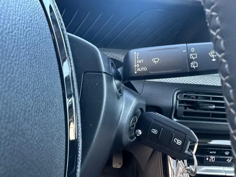 Détail intérieur côté gauche du tableau de bord noir d’une Citroën C3 2025 avec clé insérée et commandes d’essuie-glace.