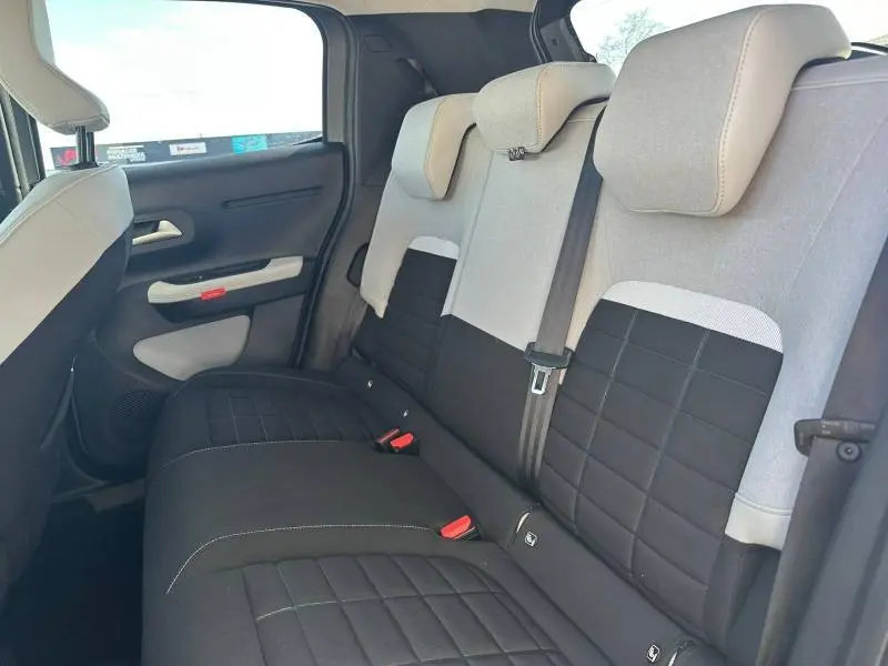 Vue intérieure arrière côté droit de la Citroën C3 2025, sièges bicolores noir et gris avec appuie-têtes intégrés.