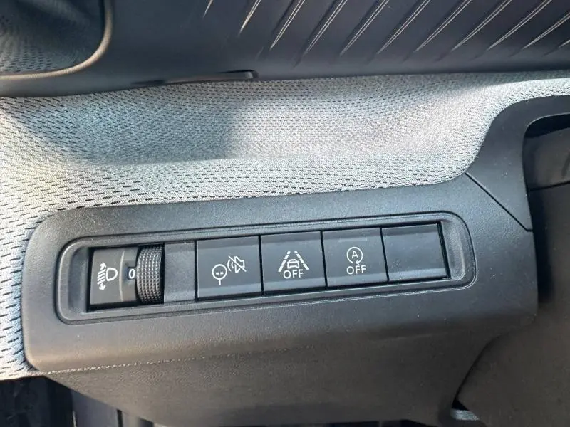 Gros plan sur les commandes de réglage d'éclairage et d'aides à la conduite dans une Citroën C3 noire, version 1.2 Turbo 100ch MAX.