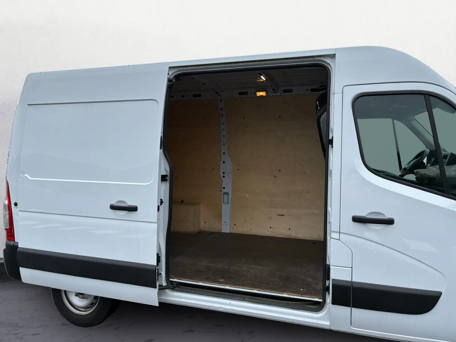 Vue latérale droite d’un Renault Master blanc 2024 avec porte coulissante ouverte montrant l’intérieur en bois du coffre.