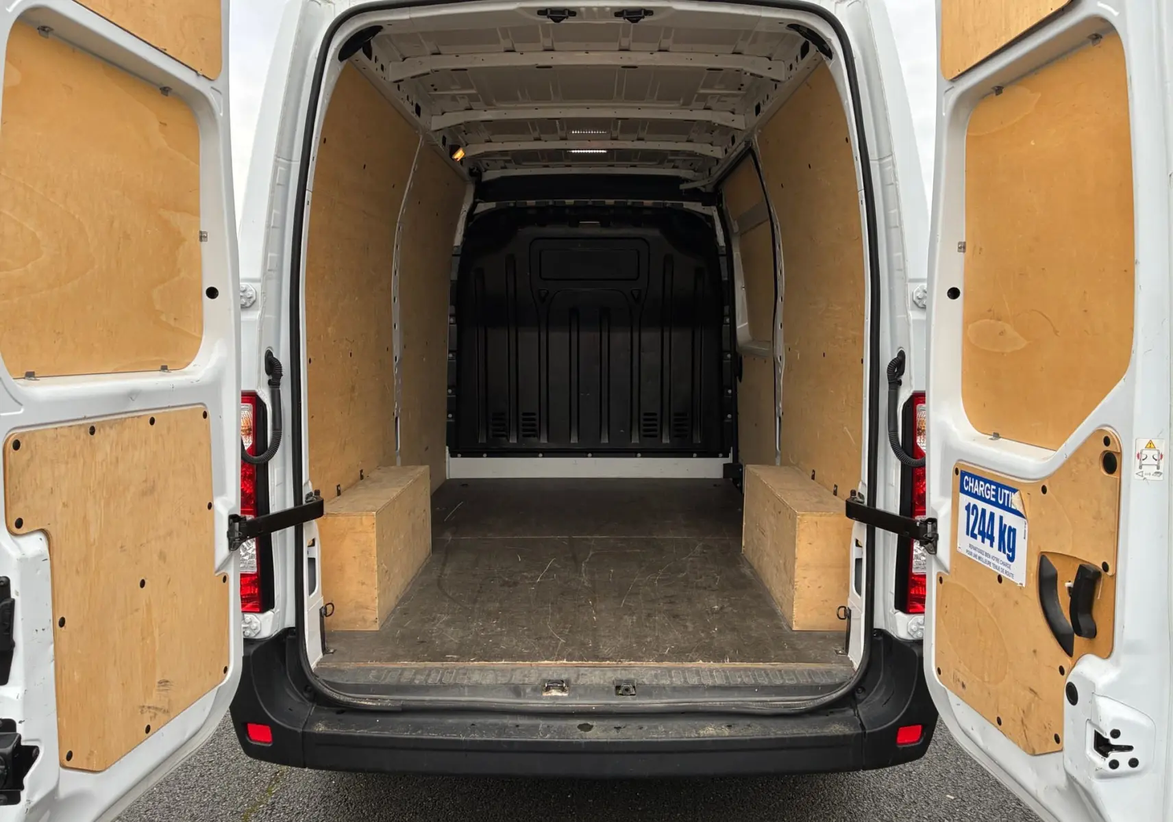 Vue arrière ouverte du Renault Master blanc 2024, montrant l'intérieur utilitaire avec parois et plancher en bois.