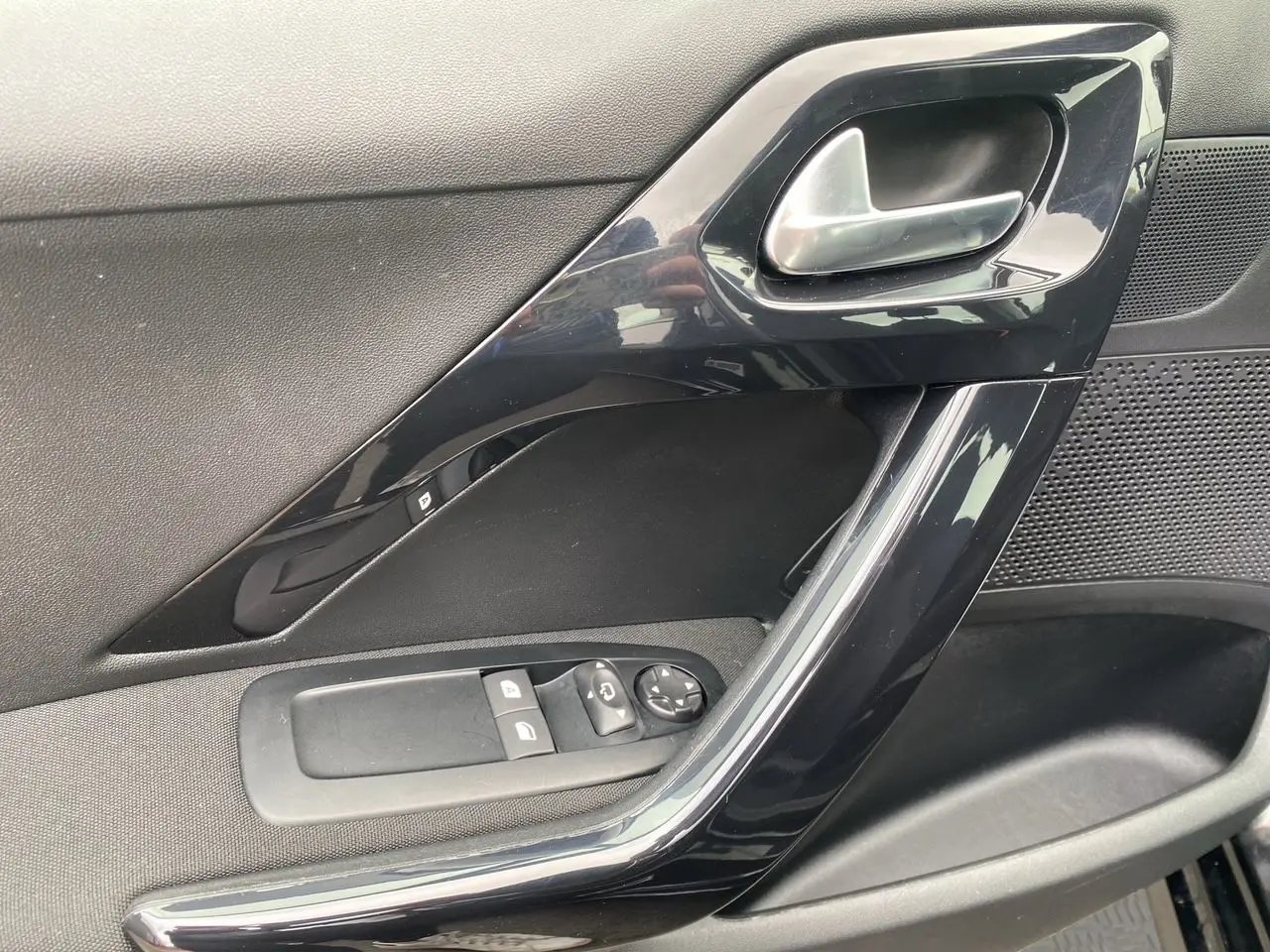 Détail de la porte côté gauche noire de la Peugeot 208 AFFAIRE avec commandes électriques et poignée argentée.