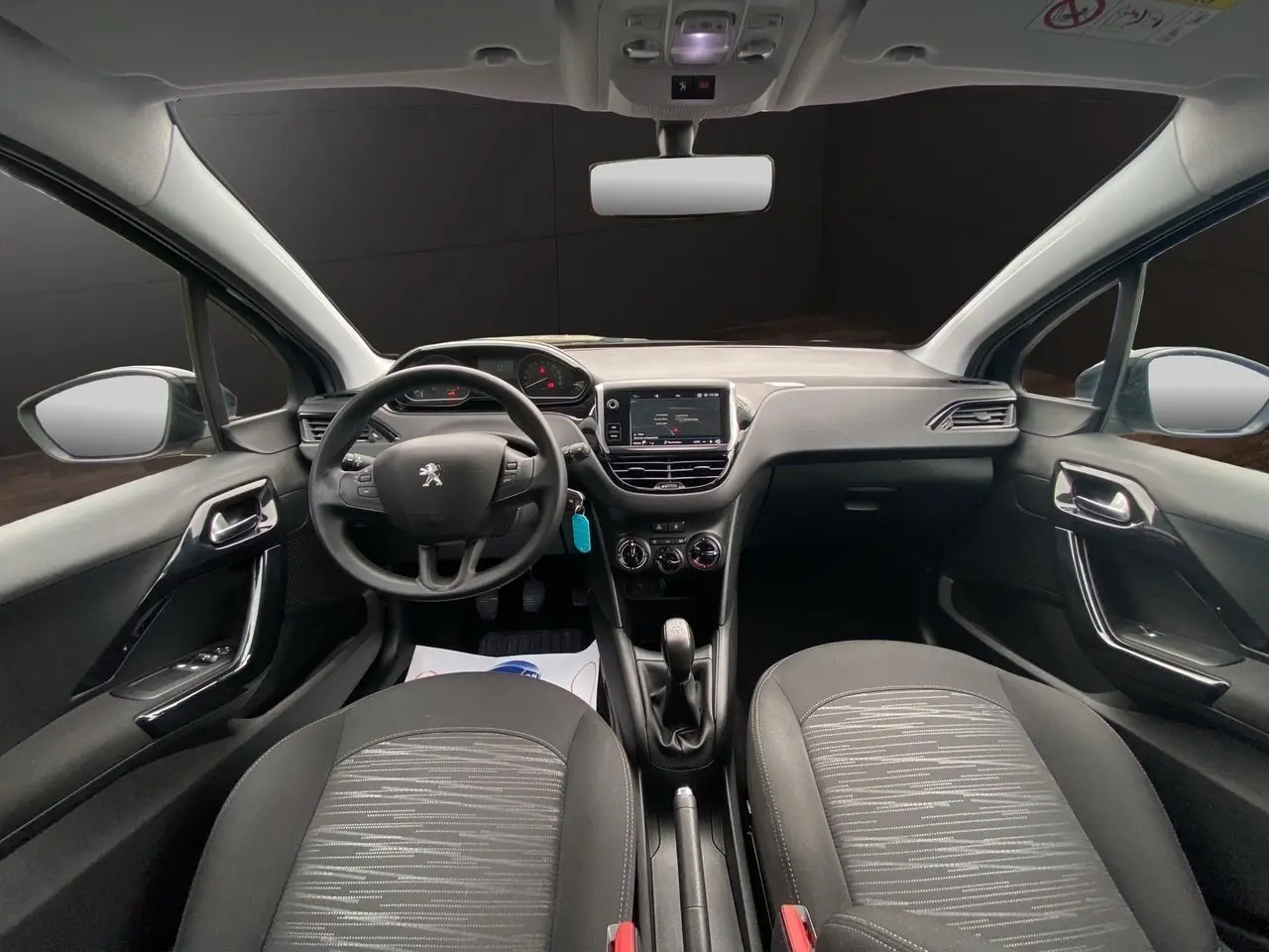 Intérieur noir de la Peugeot 208 AFFAIRE 2019, vue frontale du tableau de bord avec volant et écran GPS central.