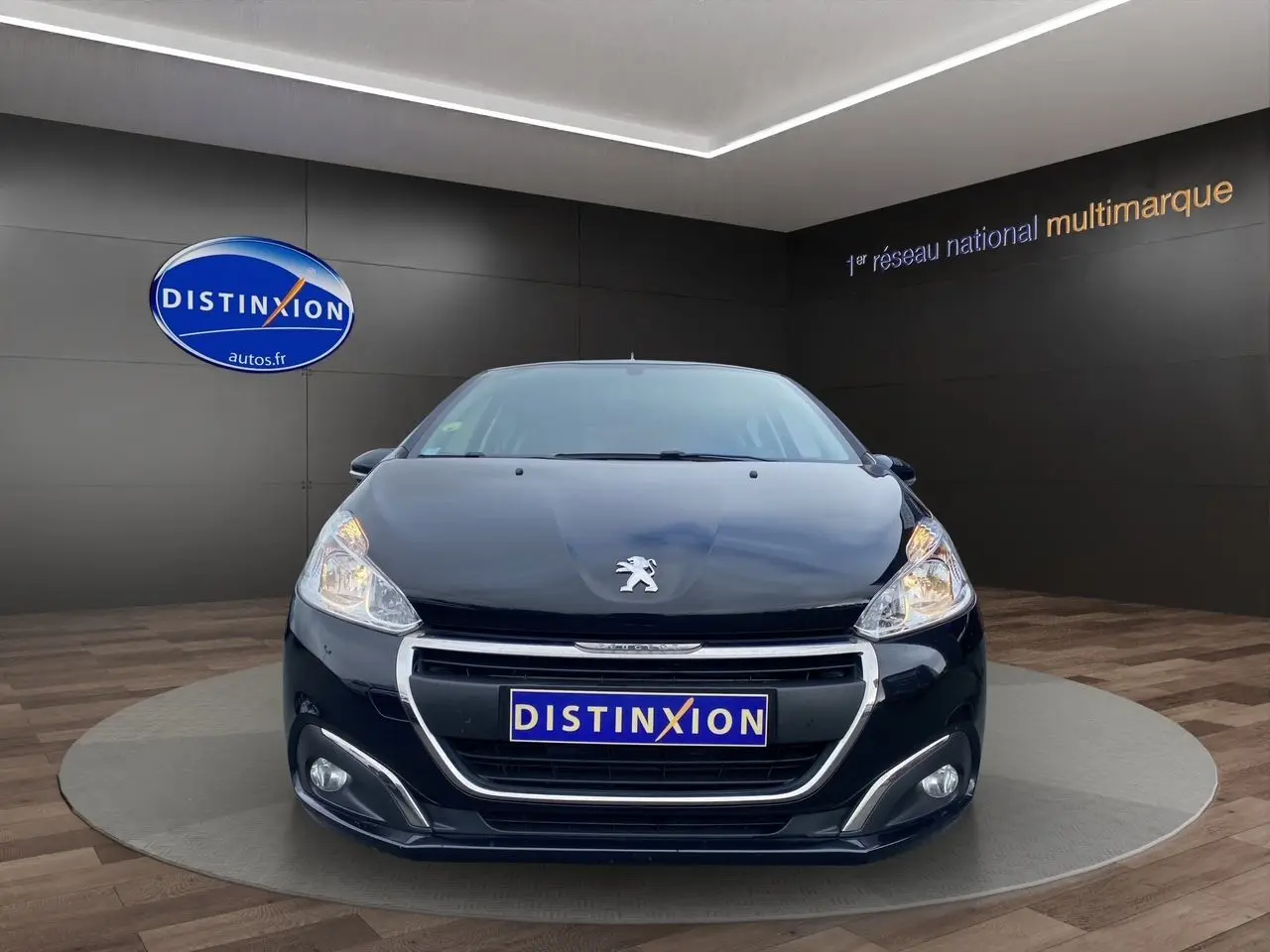 Peugeot 208 Affaire noir vue de face, mettant en valeur sa calandre chromée et ses phares allumés.