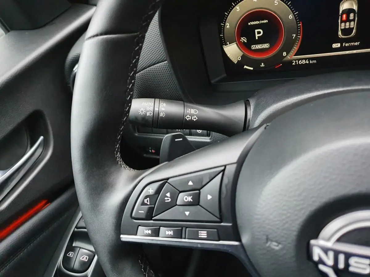 Gros plan sur le volant noir du Nissan Juke 2025 avec commandes multifonctions et compteur digital en arrière-plan.