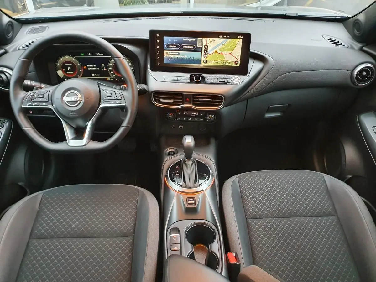 Intérieur du Nissan Juke 2025 avec tableau de bord moderne, écran tactile 12,3 pouces et console centrale avec boîte auto.
