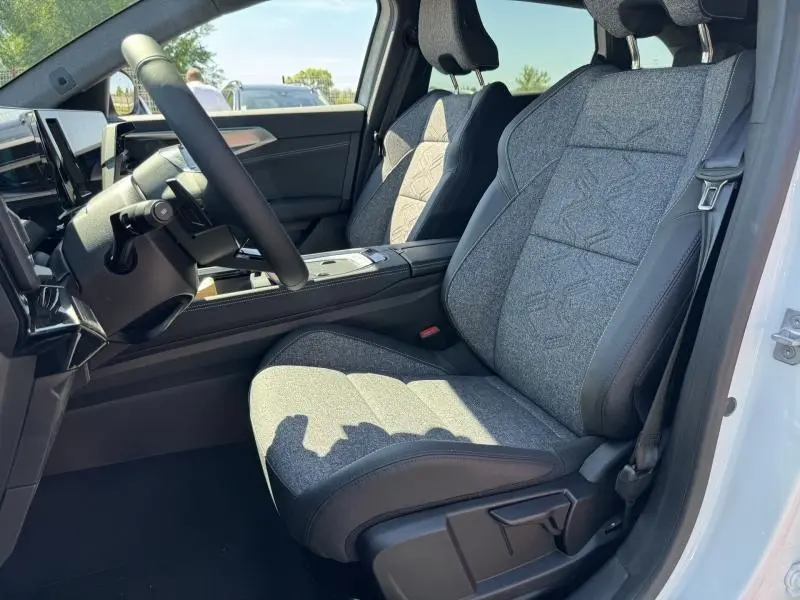 Vue intérieure côté conducteur du Renault Austral 2025, sièges tissu gris clair avec contours noirs et volant multifonction.