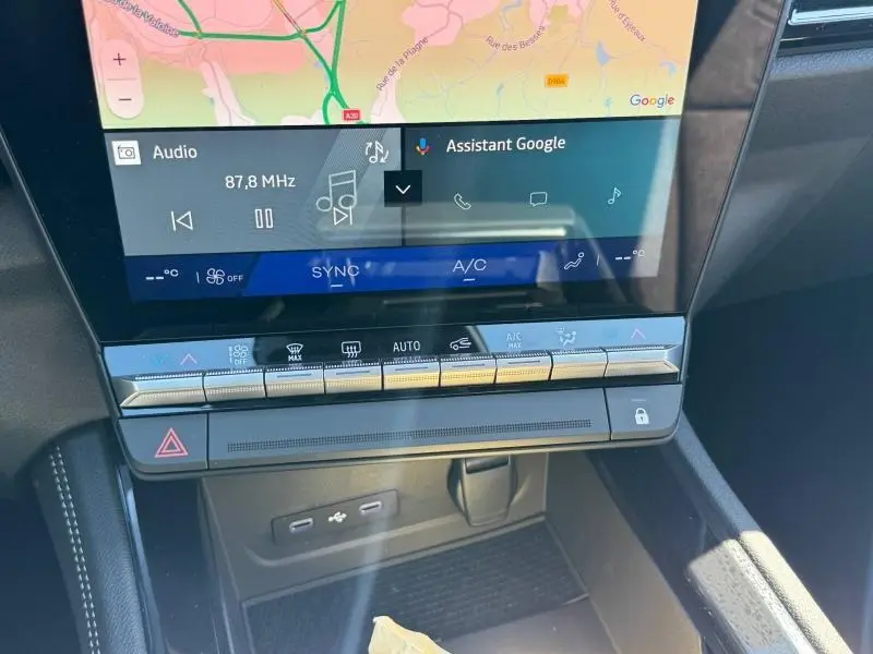 Gros plan sur l'écran tactile central et la console de climatisation du Renault Austral rouge 2025, avec commandes tactiles et ports USB visibles.