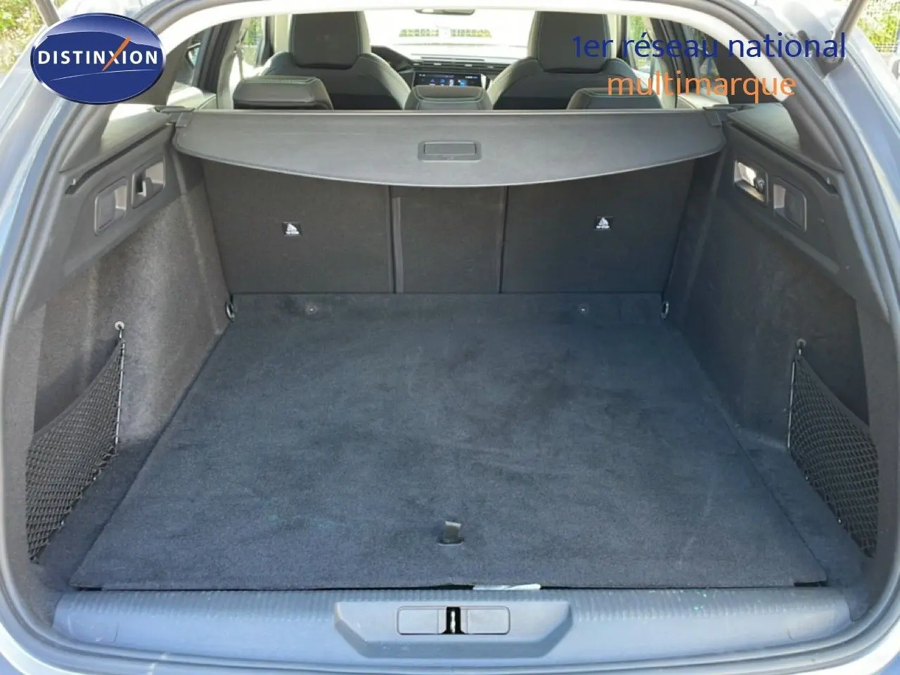 Coffre ouvert vu de l'arrière d'une Peugeot 308 SW gris Artense, montrant un espace de chargement spacieux et tapis noir.