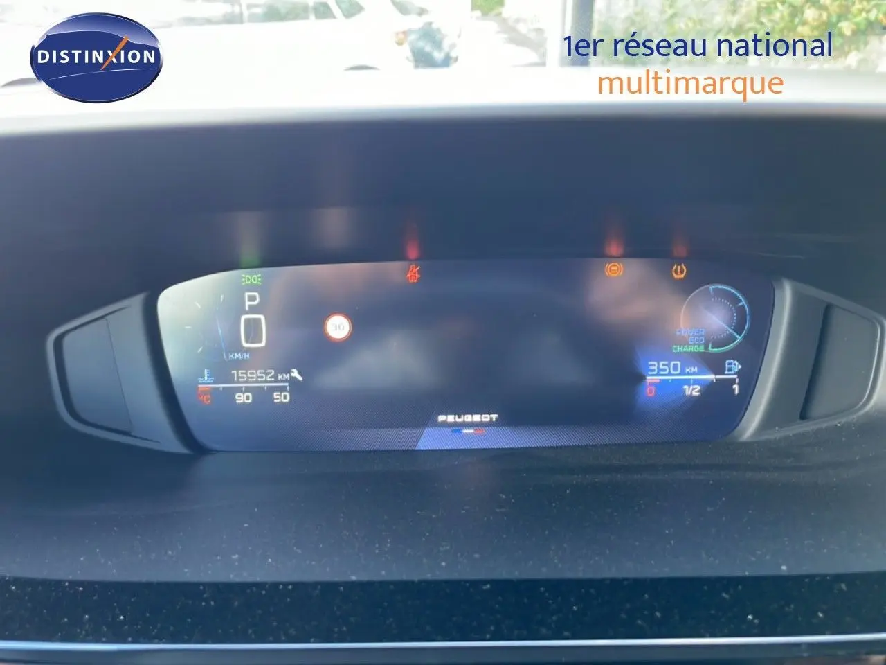 Tableau de bord numérique de Peugeot 308 SW gris, affichant la vitesse, autonomie et indicateurs en vue frontale rapprochée.