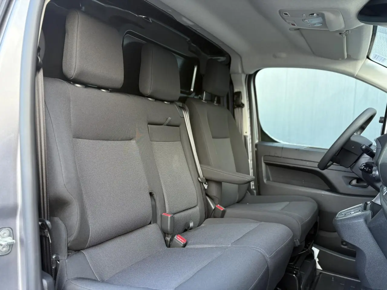 Intérieur du Citroën Jumpy XL 2025 en gris, vue latérale des sièges avant et banquette passager double.