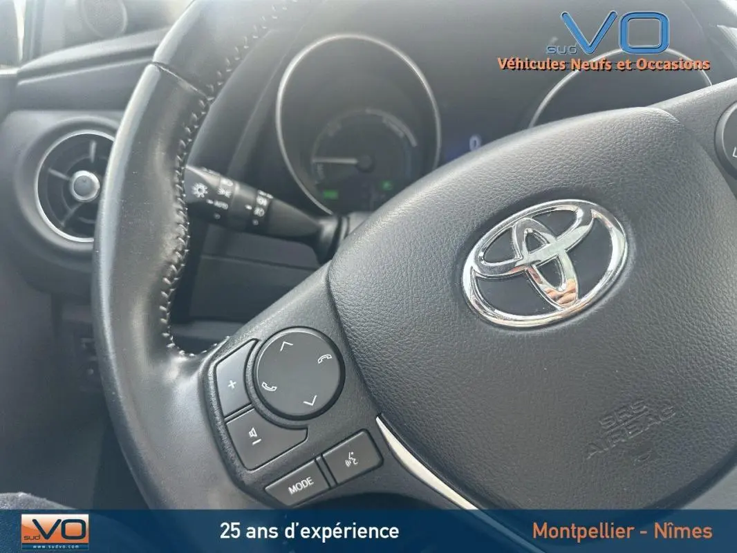 Gros plan sur le volant multifonctions noir de la Toyota Auris Business Hybride 2016 avec commandes audio intégrées.