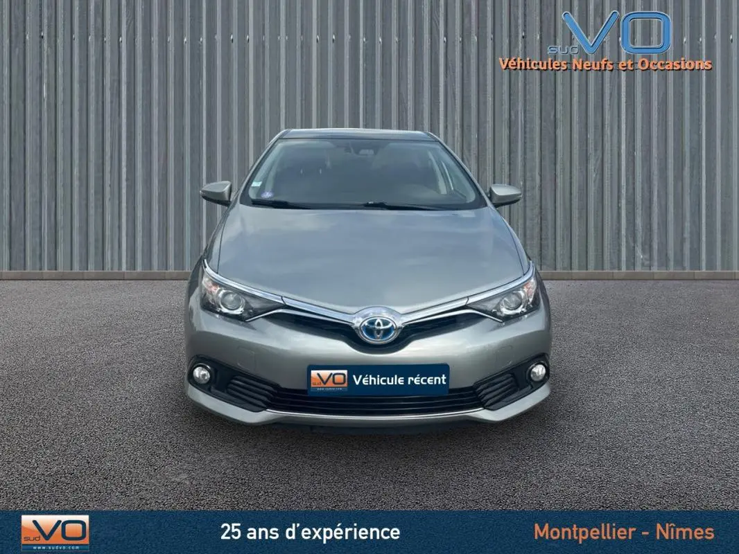Vue avant d'une Toyota Auris Business Hybride 136h gris clair avec phares antibrouillard et calandre chromée.