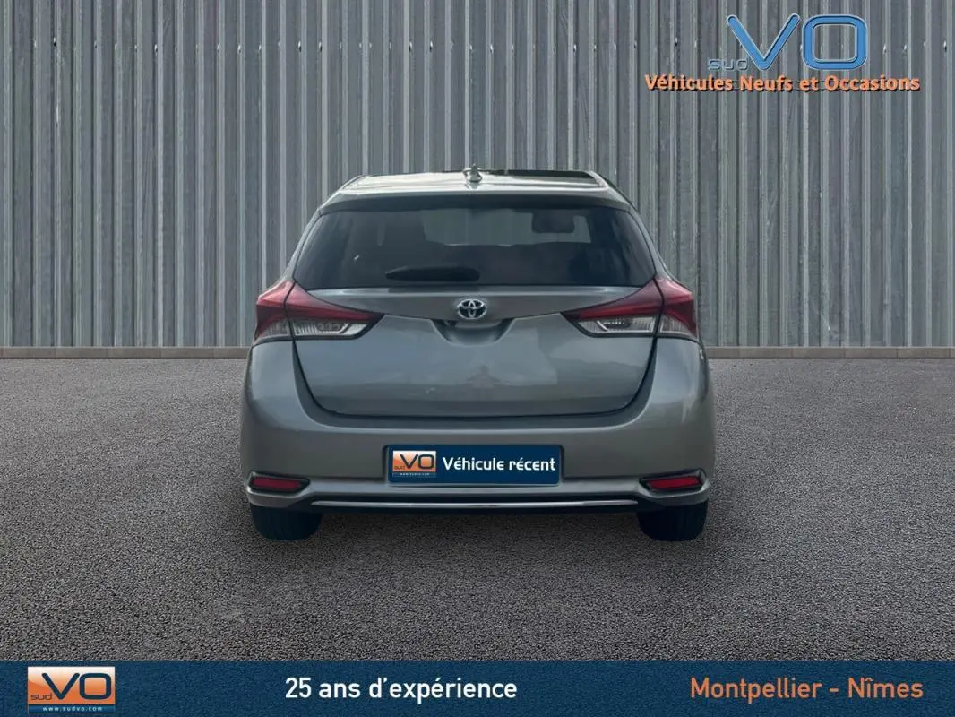 Vue arrière d'une Toyota Auris Business Hybride gris clair de 2016 avec feux arrière et plaque d'immatriculation visible.