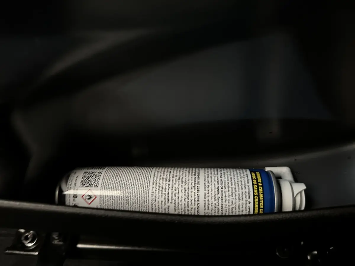 Gros plan sur une bombe aérosol dans le rangement intérieur d'une Aixam Ambition E City Pack rouge 2025 électrique.