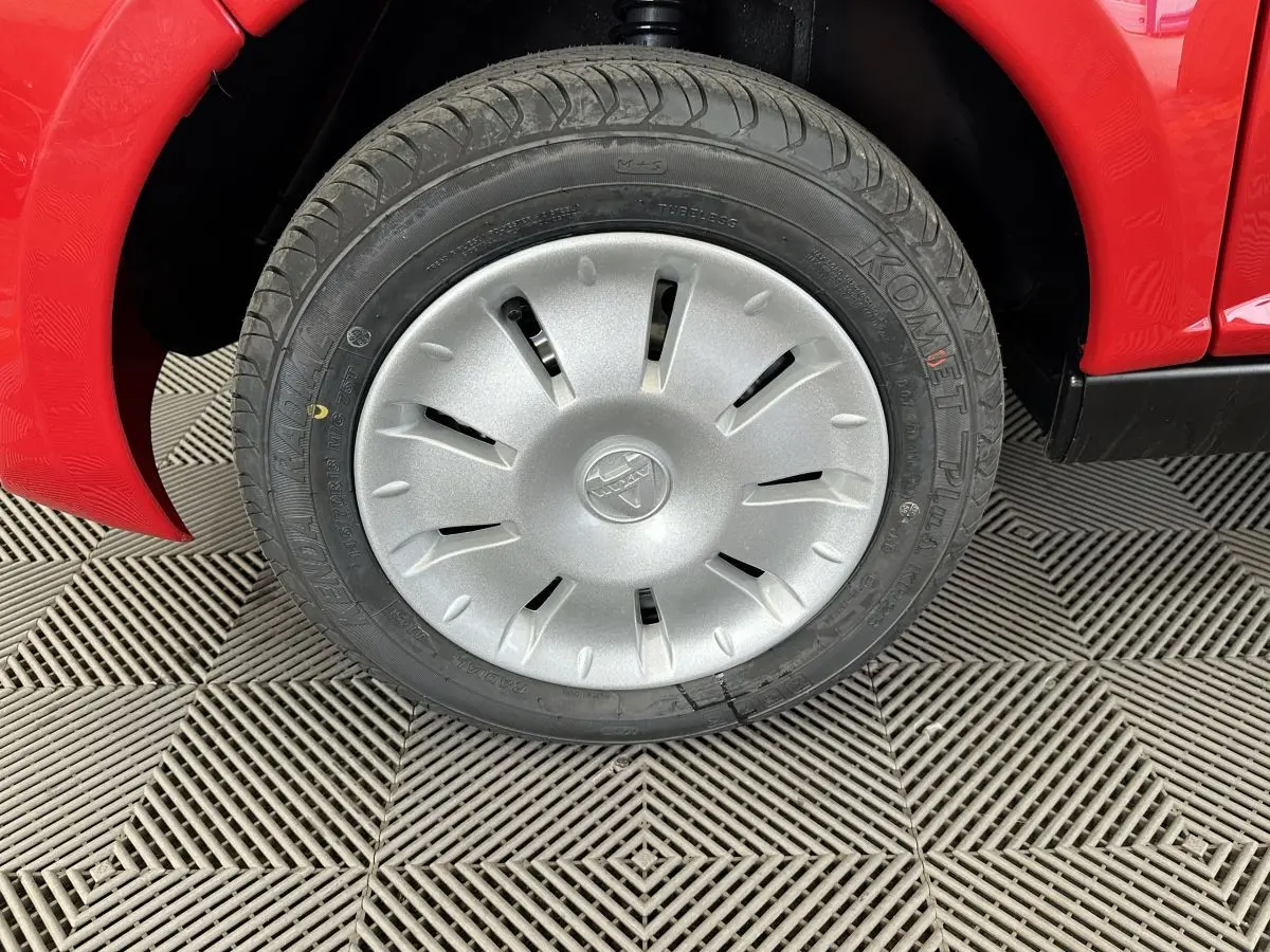 Gros plan sur la roue avant gauche d'une Aixam Ambition E City Pack rouge 2025 avec enjoliveur argenté.