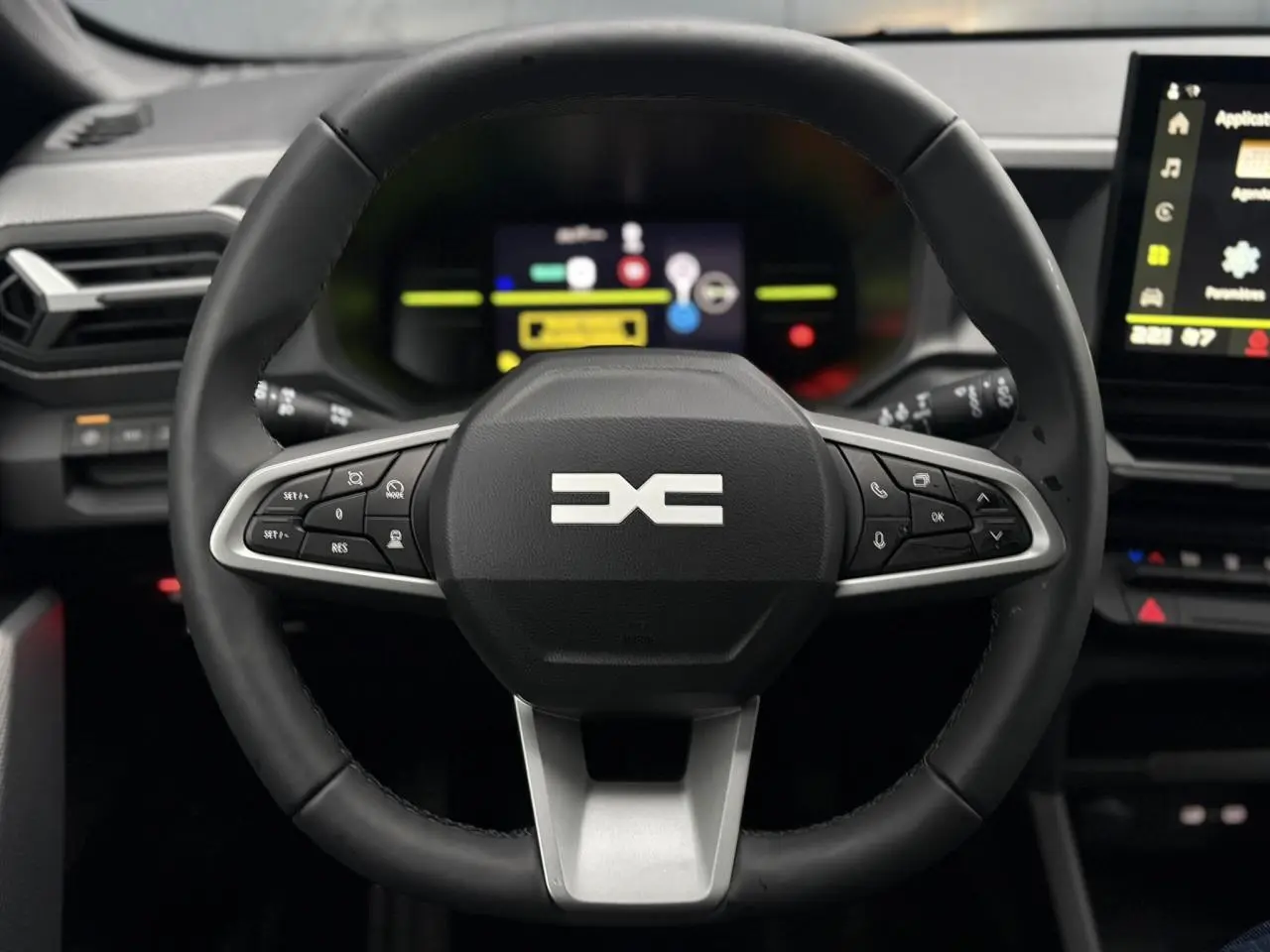 Vue rapprochée du volant noir du Dacia Duster 2026 avec commandes intégrées et tableau de bord digital en arrière-plan.