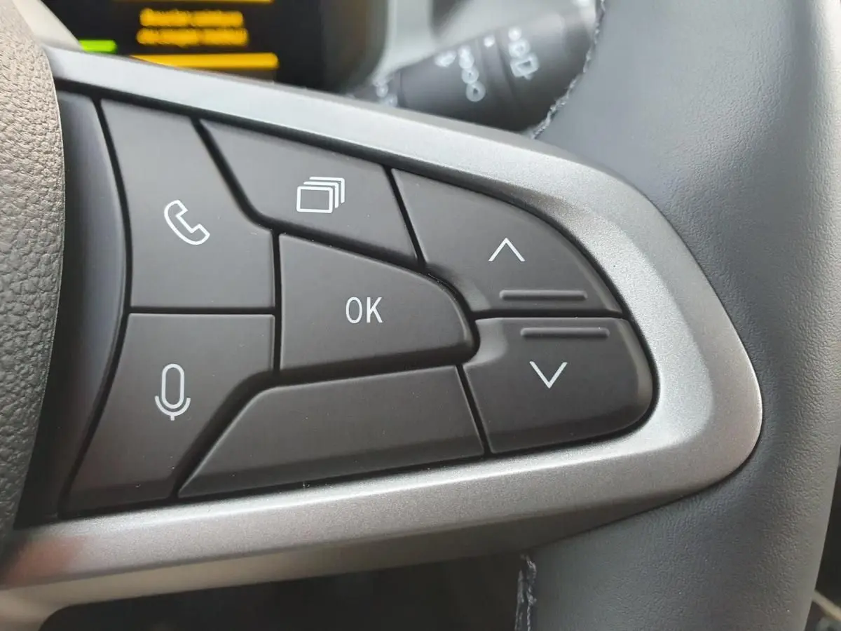 Gros plan sur les commandes multifonctions au volant du Dacia Bigster 2026, boutons noirs avec contour argenté.