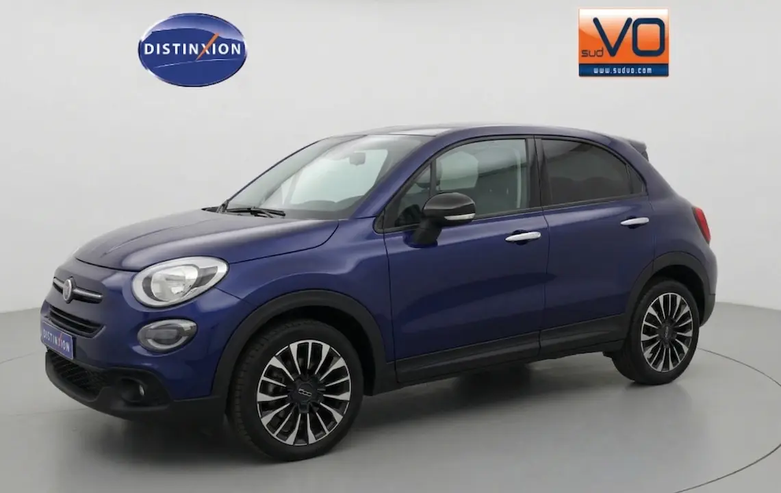 Vue 3/4 avant droit d’un FIAT 500X bleu 2024 avec jantes classiques noires et argent, dans un studio lumineux.