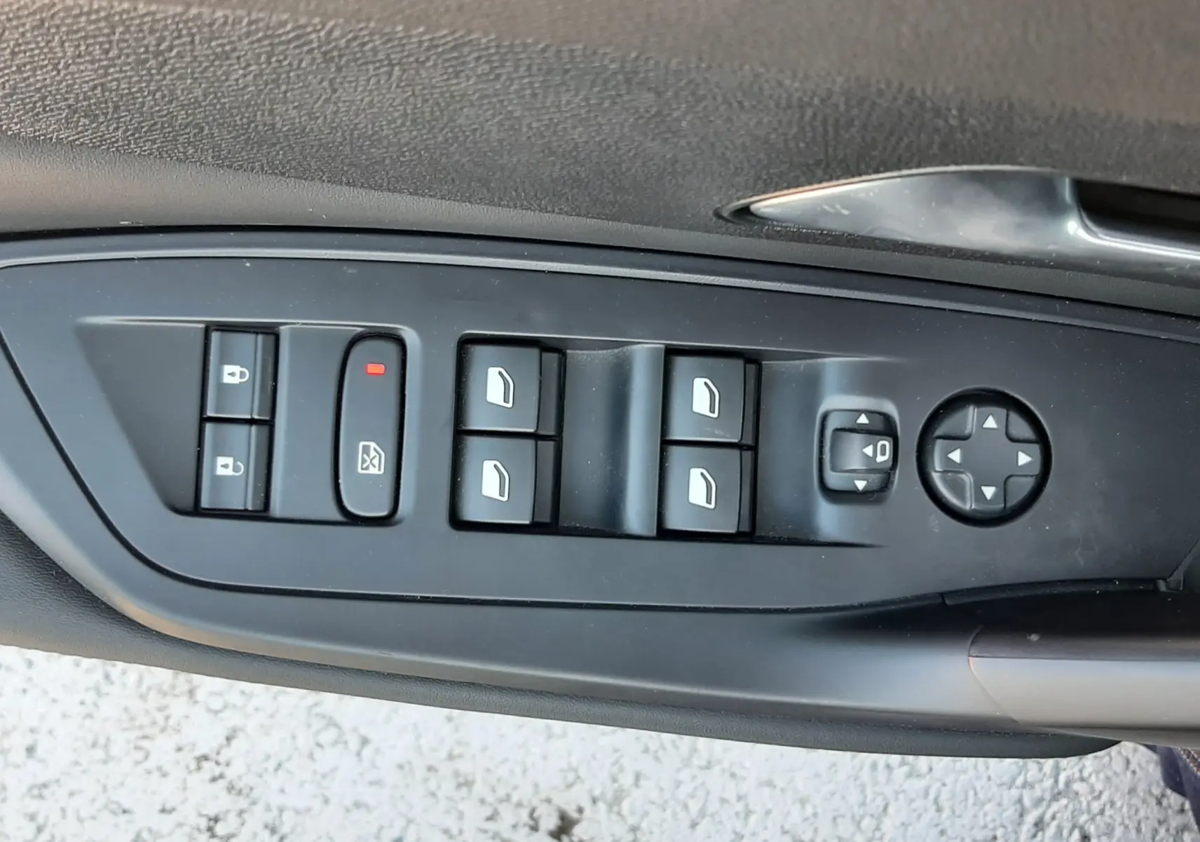 Gros plan sur les commandes de lève-vitres et rétroviseurs côté conducteur d'une Peugeot 308 SW gris selenium 2025.