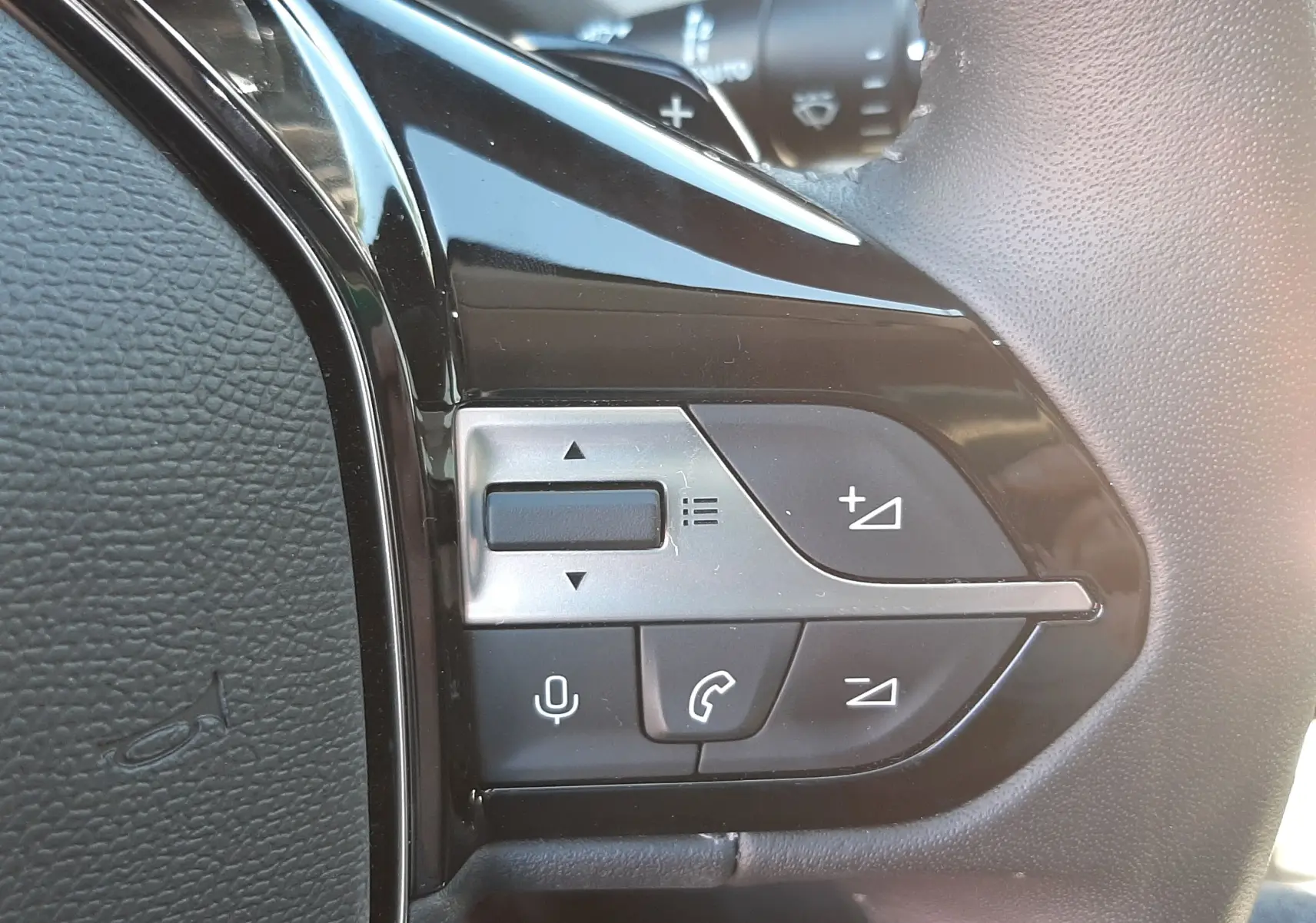 Gros plan sur les commandes multifonctions noires et argentées à droite du volant en cuir du Peugeot 308 SW gris.