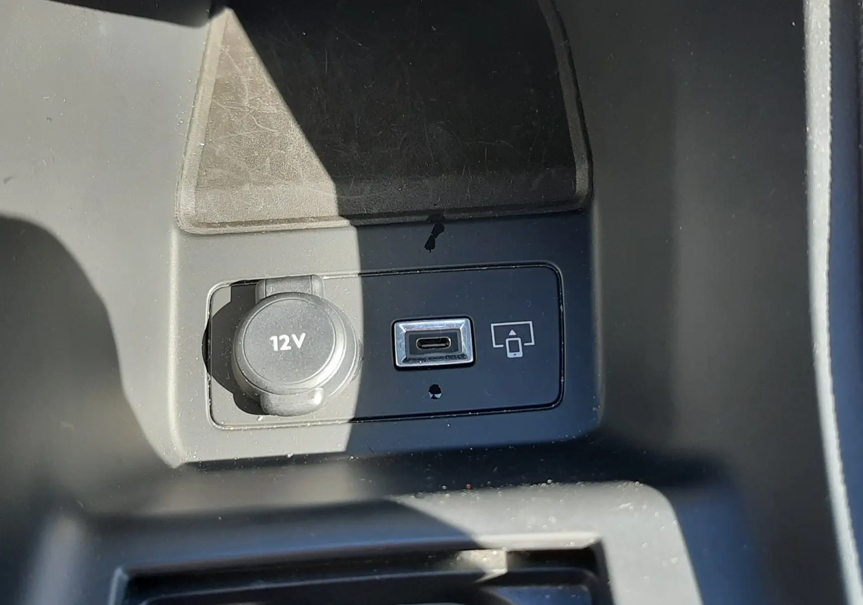 Prise 12V et port USB-C en gros plan dans la console centrale du Peugeot 308 SW Hybrid 2025 gris Selenium Metal.