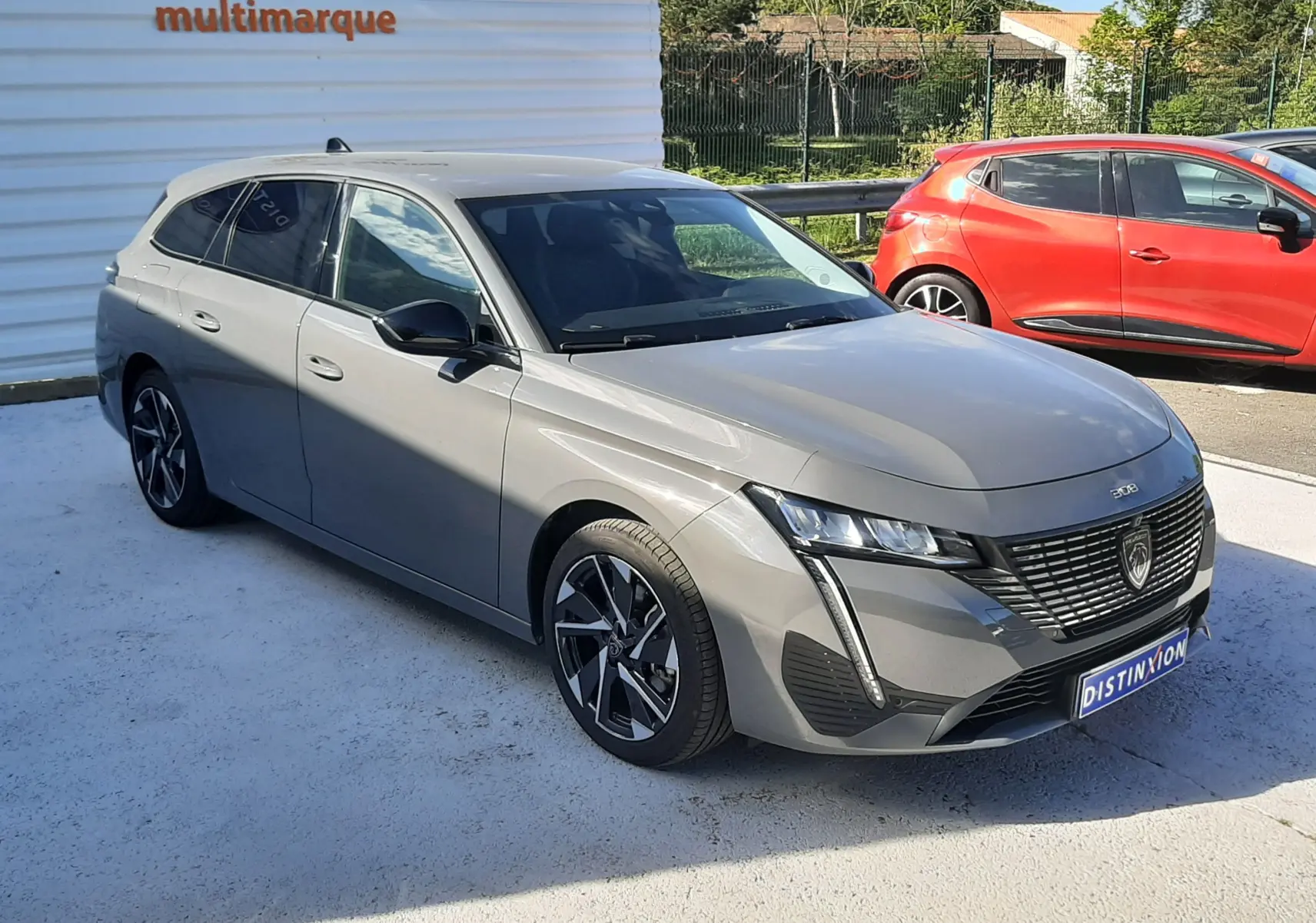 Peugeot 308 SW gris Selenium métal en vue 3/4 avant droit, avec calandre noire et jantes alliage distinctives.