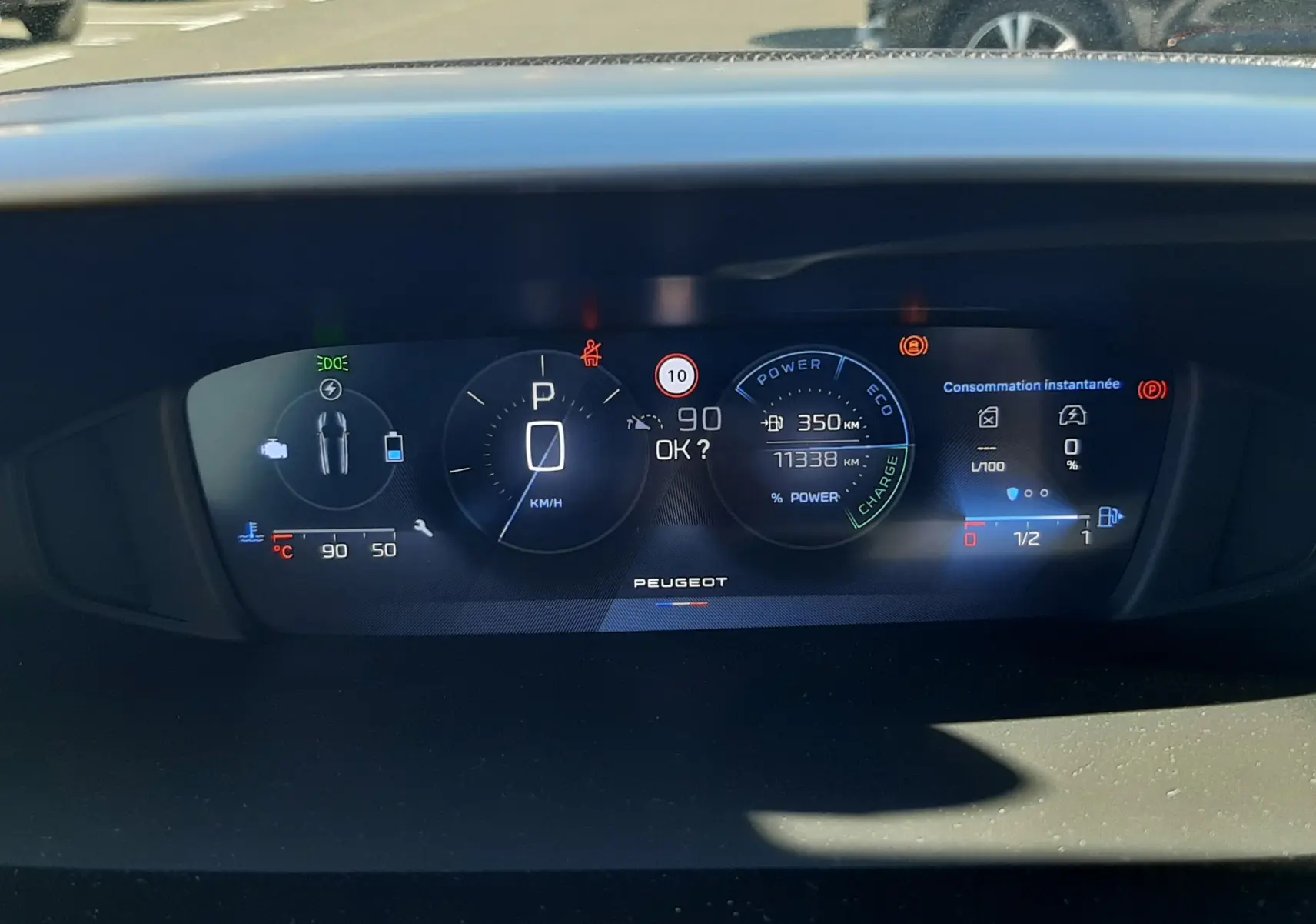 Tableau de bord numérique de Peugeot 308 SW Hybrid 2025, affichage central avec vitesse, autonomie et consommation instantanée.
