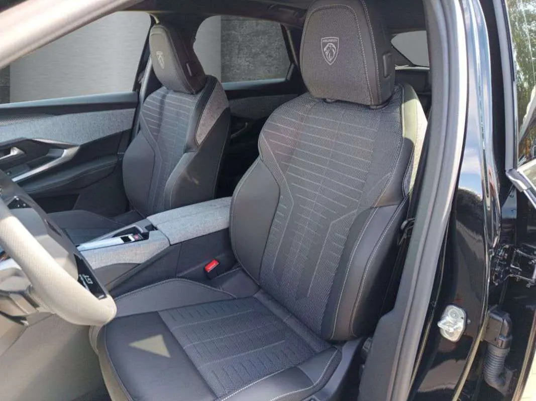 Vue intérieure côté conducteur du Peugeot 3008 New Hybrid 145 GT 360 noir perla nera, sièges avant avec logo Peugeot brodé.
