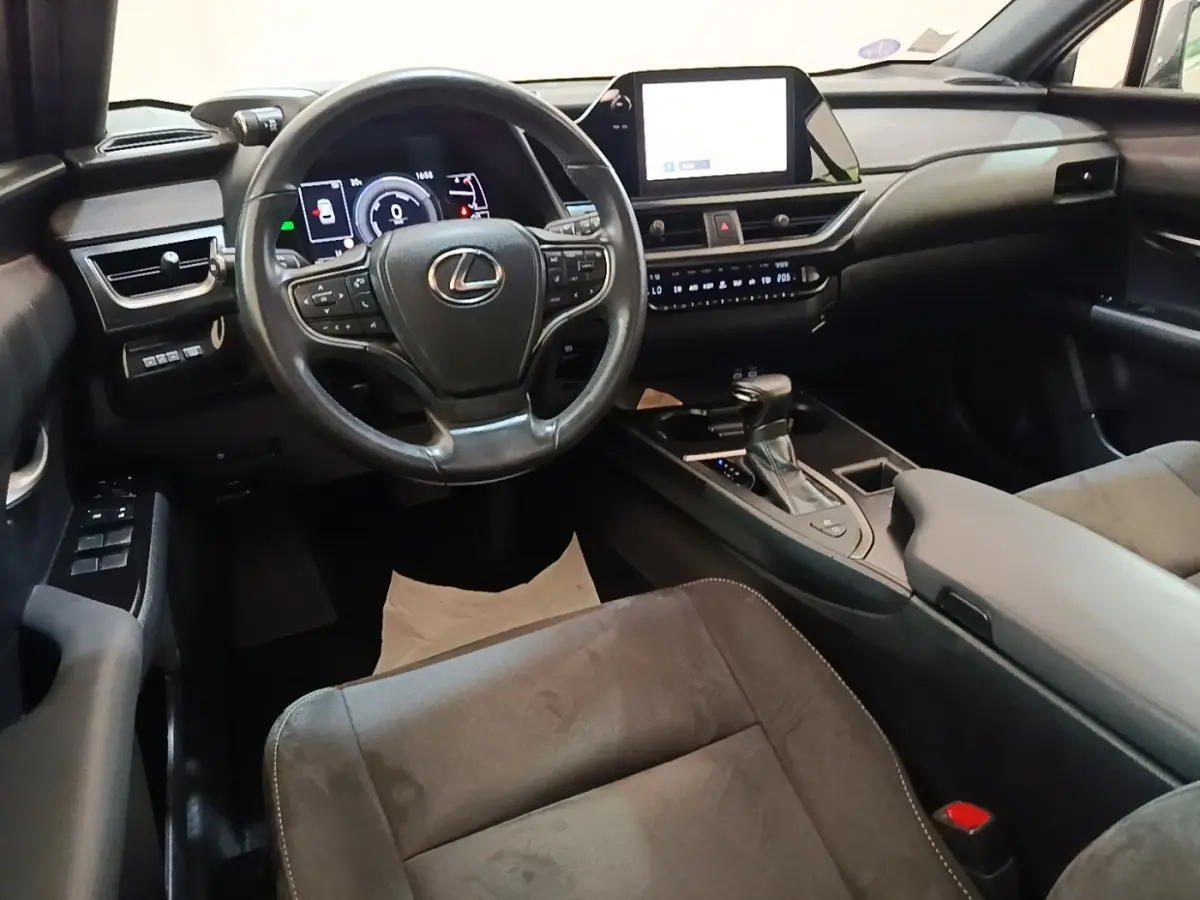 Intérieur du Lexus UX 250H 2WD gris clair, vue de face sur le volant, tableau de bord et écran tactile central.