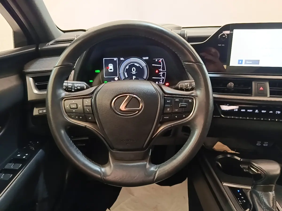 Vue centrée sur le volant cuir noir du Lexus UX 250H 2WD Pack Business avec tableau de bord digital et écran tactile.