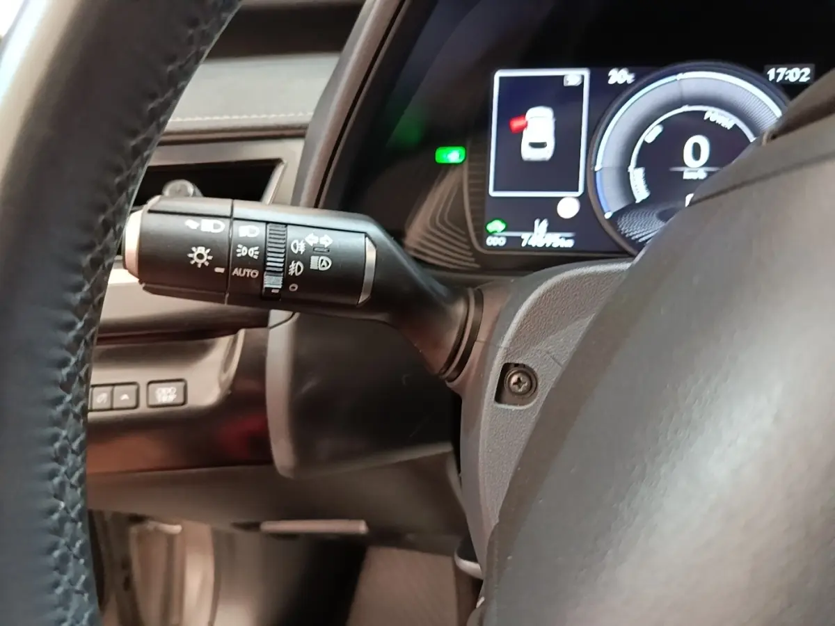 Gros plan sur le commodo gauche et le tableau de bord numérique du Lexus UX 250H gris clair, affichage multifonctions allumé.