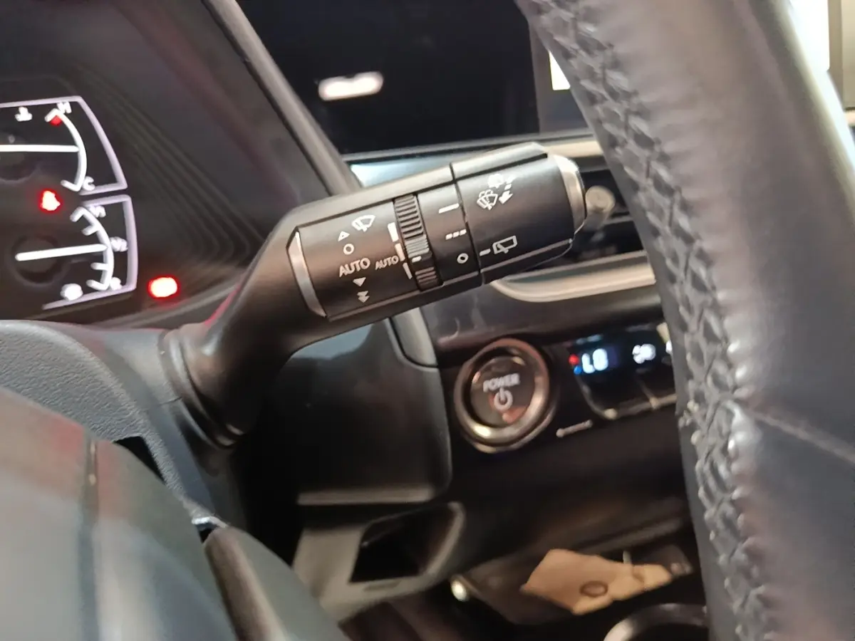 Gros plan sur la commande d’essuie-glace à gauche du volant cuir dans l’habitacle noir du Lexus UX 250H gris clair.