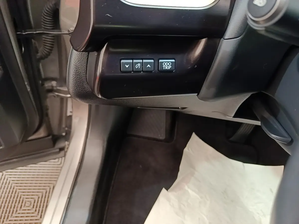 Vue intérieure côté conducteur du Lexus UX 250H gris clair, montrant les boutons de réglage du tableau de bord.