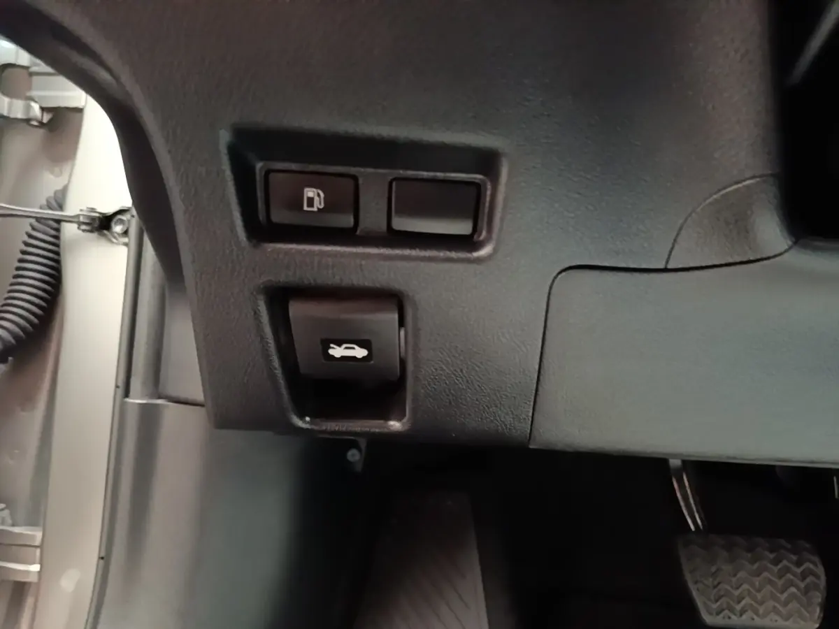 Détail des commandes d'ouverture de trappe à carburant et de capot côté conducteur d'un Lexus UX gris clair 2023.