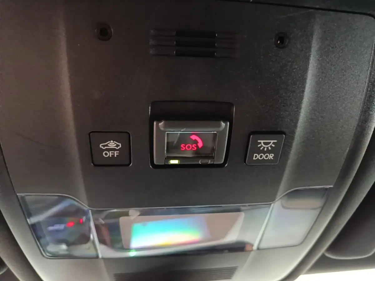 Vue rapprochée du panneau de commande intérieur au plafond du Lexus UX 250H gris clair, avec bouton SOS rouge central.