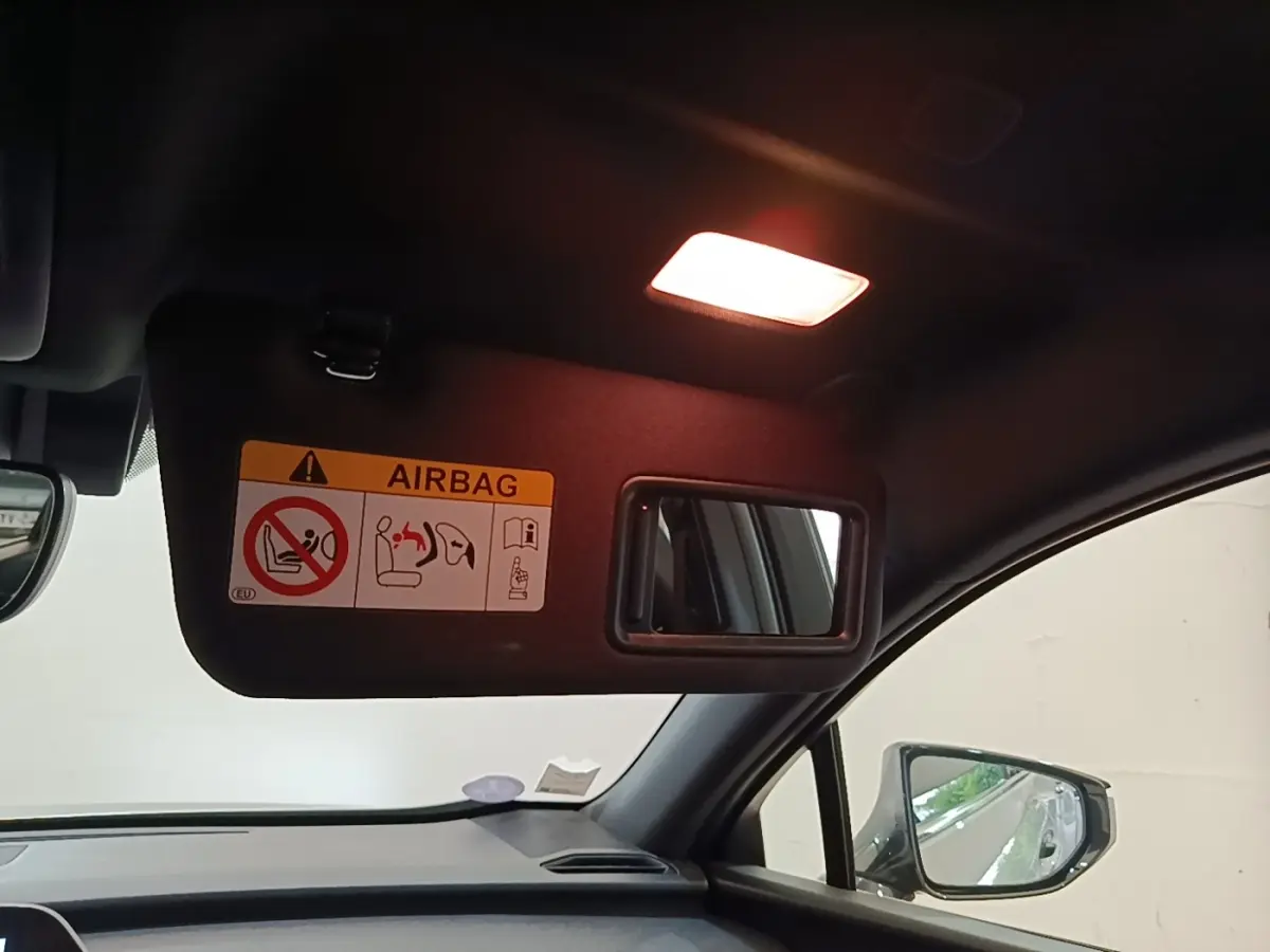 Intérieur du Lexus UX 250H 2WD gris clair, vue côté passager avec pare-soleil et miroir éclairé.