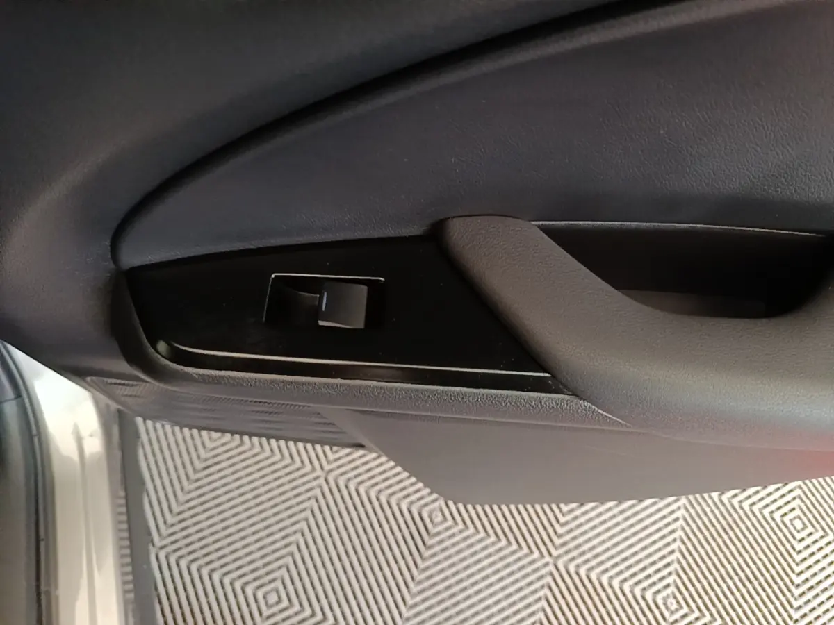 Détail de la poignée intérieure et commande de lève-vitre côté conducteur d’un Lexus UX 250H gris clair.