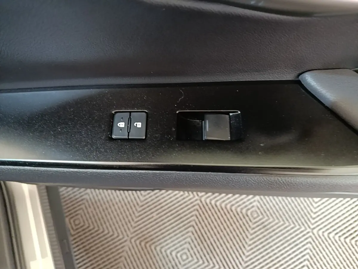 Gros plan sur les commandes de verrouillage des portes côté conducteur d’un Lexus UX 250H gris clair.