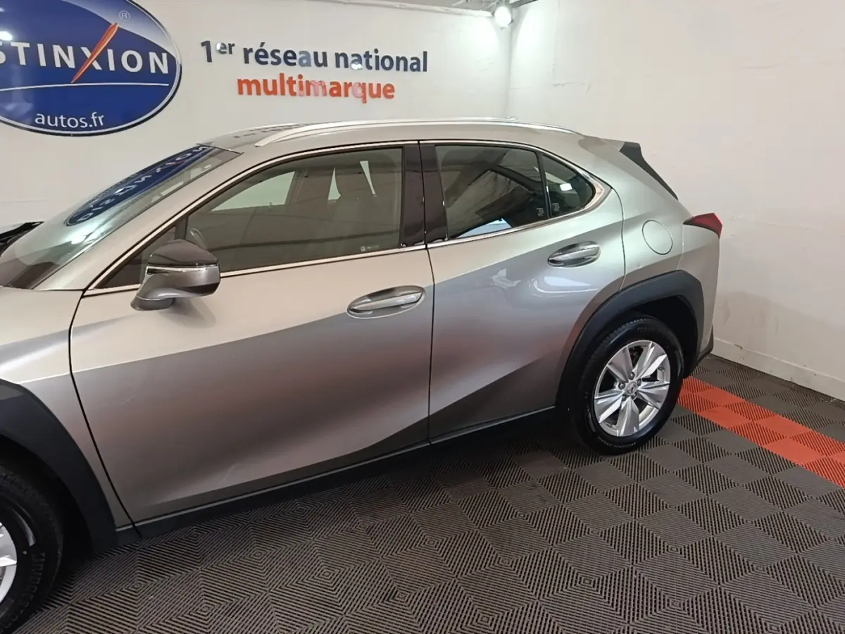Profil côté gauche du Lexus UX 250H 2WD gris clair, avec jantes alliage et rétroviseurs assortis.
